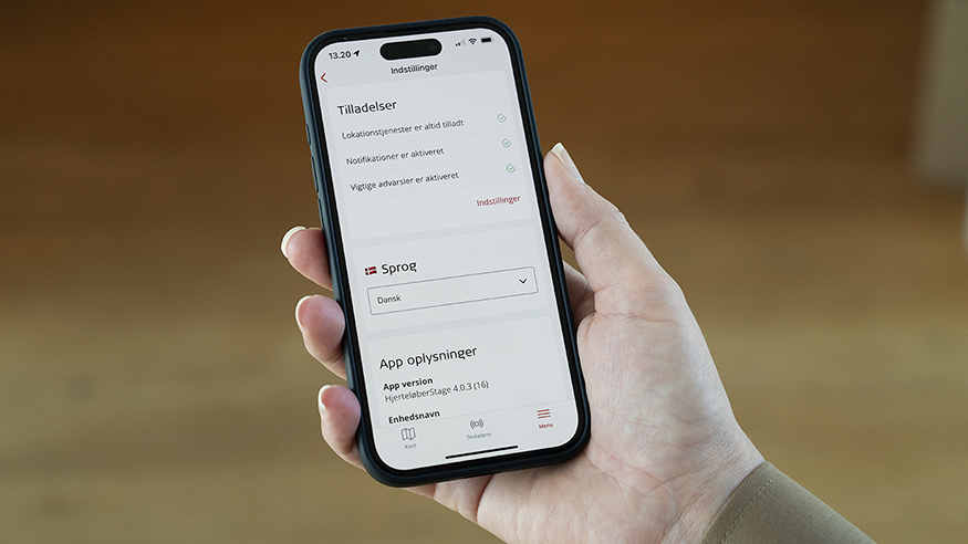  En person holder en telefon, hvor man kan se indstillinger for hjerteløber-appen